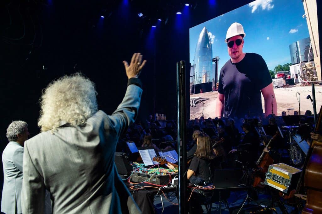 Брайан Мэй машет Илону Маску на STARMUS V, прошедшему в 2019 году / ©STARMUS